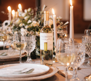 Bottle of En Primeur white wine on a candlelit wedding table set with crystal glasses and flowers
