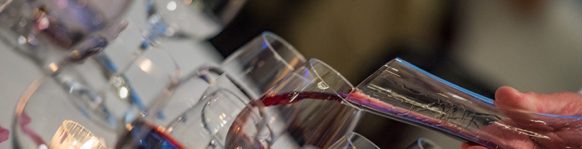 Red wine being poured from a decanter into glasses